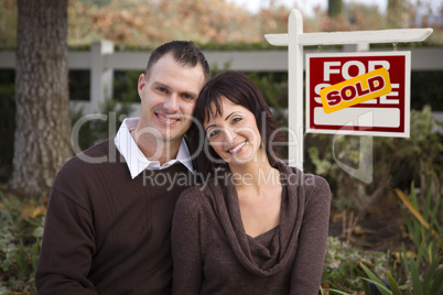 Happy Couple in Front of Sold Real Estate Sign