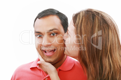 Young woman kissing her surprised boyfriend, isolated on white