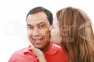 Young woman kissing her surprised boyfriend, isolated on white