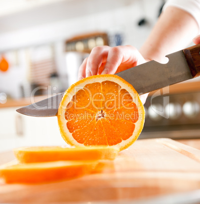 Woman's hands cutting orange