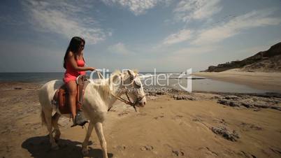 Frau reitet Schimmel am Strand