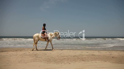 Frau reitet Pferd am Strand