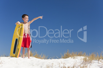 Young Boy Child on A Beach with Surfboard Pointing