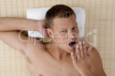 young male lying on mat ready to take spa treatment