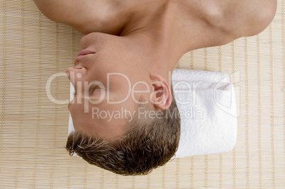 young male lying on mat ready to take spa treatment