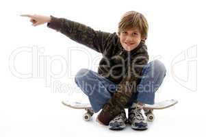 front view of boy sitting on skate and pointing