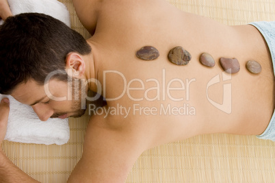 high angle view of male relaxing for hot stone treatment