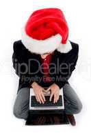 sitting male with christmas hat and working on laptop