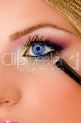 close view of young model putting eyeliner