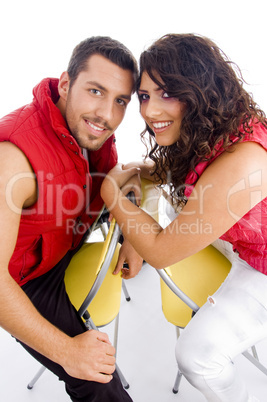 young amorous couple sitting on chair and looking at camera