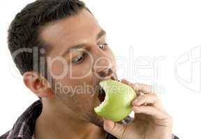 man eating green an apple and looking like askance of his apple