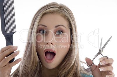 surprised woman holding scissor and comb