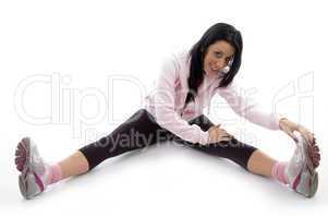 side view of smiling woman stretching her legs on white background