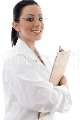 side view of smiling doctor holding writing pad on white background
