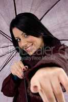 front view of pointing woman holding umbrella on white background