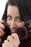 close view of model covering face with overcoat on white background