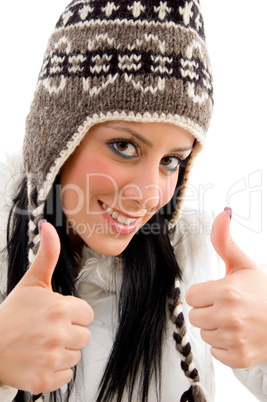 front view of smiling woman with woolen cap and thumbs up on white background