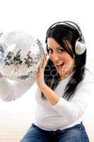 front view of female listening music and holding disco ball on white background