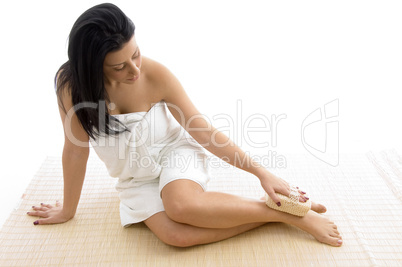 front view of sitting female scrubbing her body with scrubber