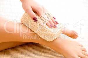 close view of woman scrubbing her leg against white background