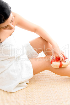 high angle view of woman scrubbing her legs on white background