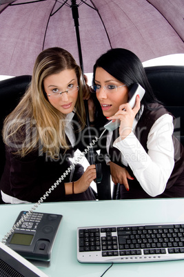 executive busy on phone call and her employee holding umbrella