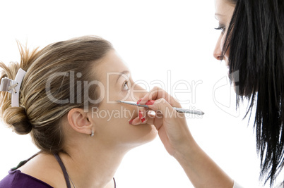 model getting eye makeup from beautician