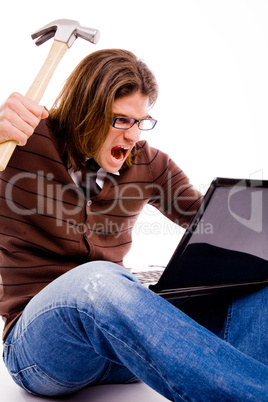 side pose of angry man striking monitor with hammer