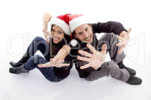 young couple wearing christmas hat with hand gesture