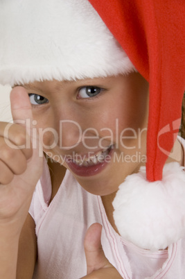 happy little girl wearing christmas hat showing hand gesture