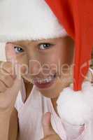 happy little girl wearing christmas hat showing hand gesture