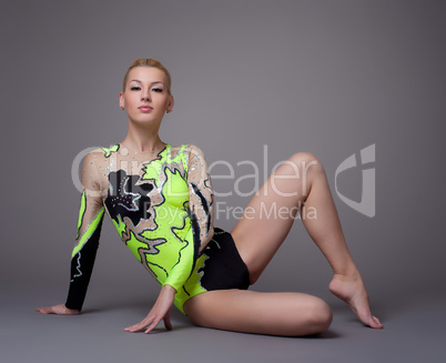 Young woman in gymnast suit posing on grey