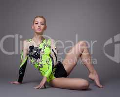 Young woman in gymnast suit posing on grey