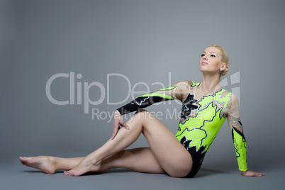 Young woman in gymnast suit posing on grey