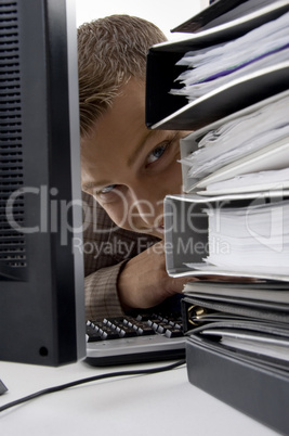 young man looking between the files and computer