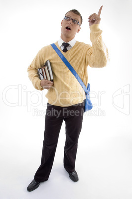 young student carrying bag and books pointing upwards