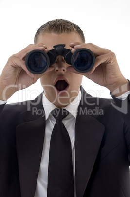 handsome young executive looking through binoculars and giving shocking expression