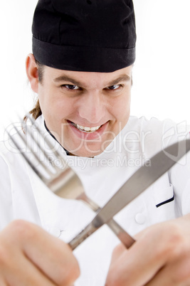 close up of young chef holding fork and knife crossed
