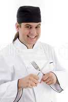 smiling young male chef holding fork and knife