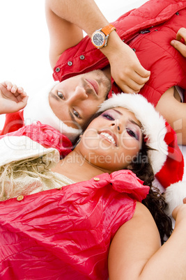cheerful young couple wearing christmas hat lying down on floor