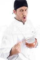 young chef holding bowl and chopstick and looking at camera