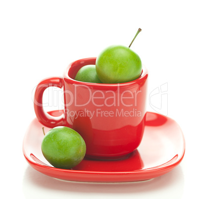 green plum  in the red cup isolated on white