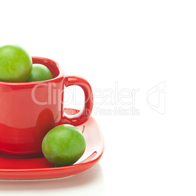 green plum  in the red cup isolated on white