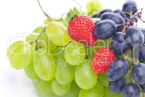 bunch of white and black grapes and strawberries isolated on whi