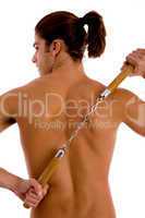 back pose of shirtless man holding nunchaku