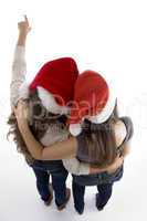 friends in christmas hats pointing backwards