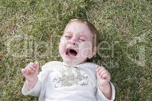 adorable child crying and lying in the garden