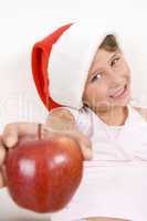 smiling little girl with christmas hat showing apple