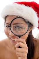 young woman with christmas hat looking through magnifier