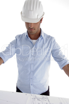 young caucasian architect in helmet having a look at blueprints
